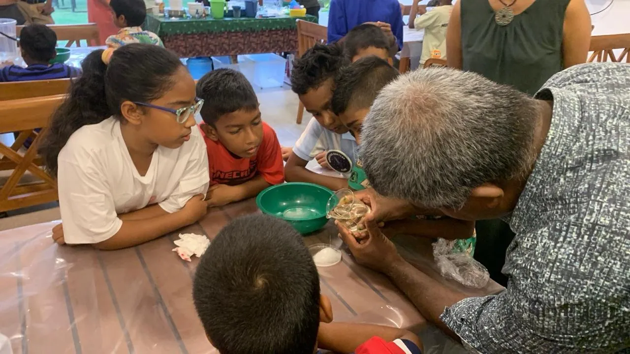 Children leaning over a table watching Mr. N run an experiment