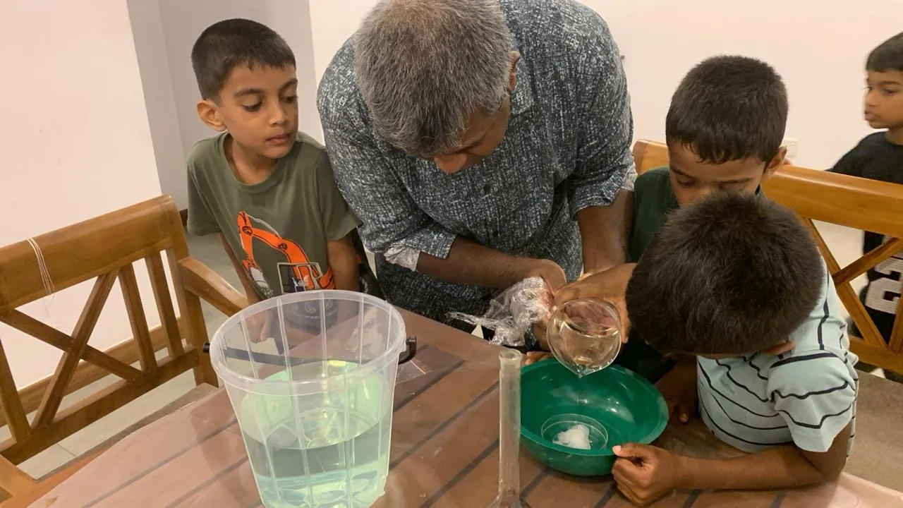Mr. N pouring a dry ice mixture into a green bowl surrounded by watching children