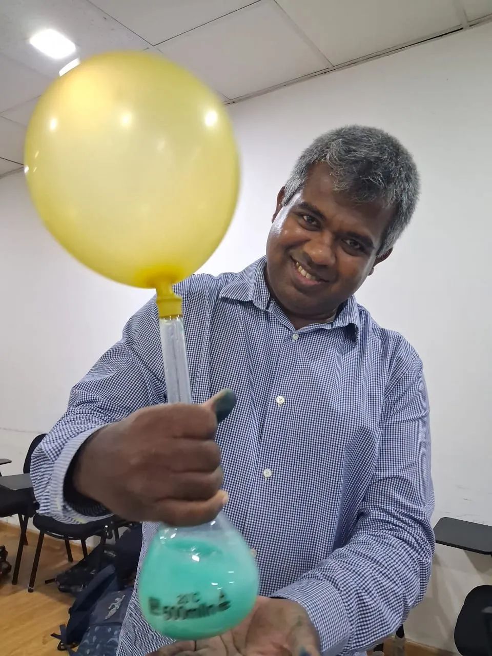 Mr. N smiling as he holds a flask with a balloon inflating on top of it
